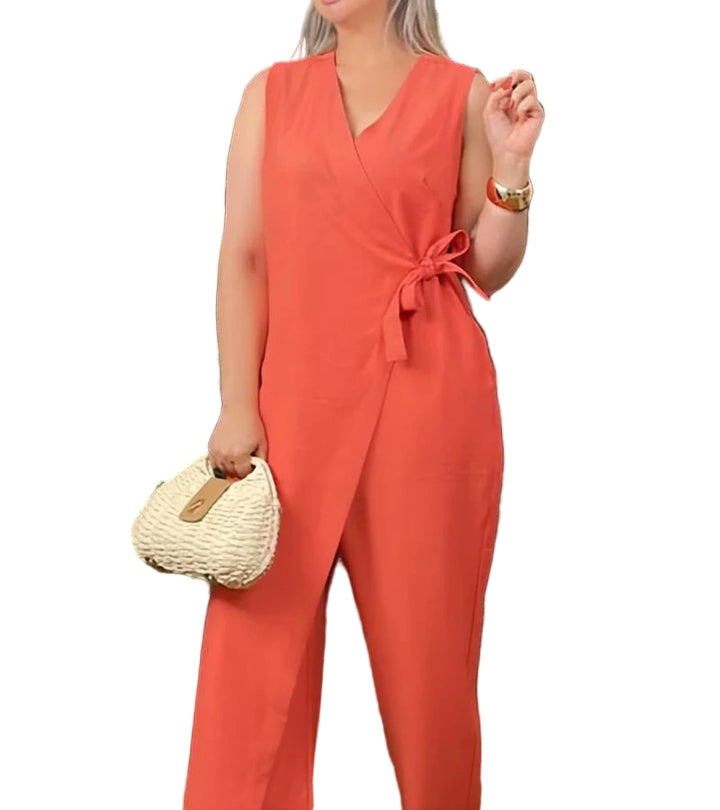 Woman wearing a coral jumpsuit holding a straw bag on a white background